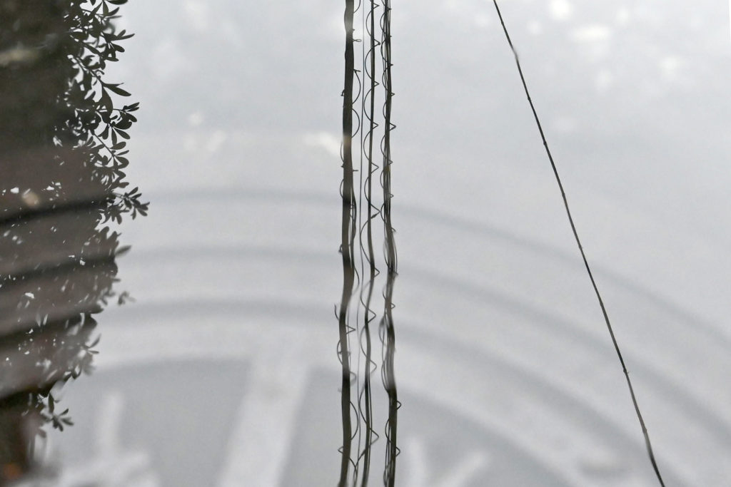 マンホールに張った水面に映る螺旋電線
